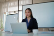 © mojo_cp - Confident businesswoman sitting at modern office desk reviewing reports and focusing on company tasks