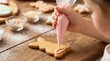 © NN AI - Child decorating bunny shaped cookie with pink icing. Easter baking activity on wooden table. Close up of hand piping frosting on gingerbread biscuit