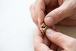 © Stitch - A person is carefully changing the small round battery in a modern behind-the-ear hearing aid.
