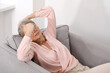 © New Africa - Unhappy senior woman feeling fatigue on sofa at home, space for text