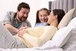 © New Africa - Pregnant woman, her husband and daughter on bed at home