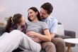© New Africa - Pregnant woman, her husband and daughter on sofa at home