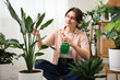 © New Africa - Woman spraying beautiful potted houseplant with water indoors