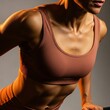 © Image - A fit woman in a brown sports bra is captured in a dynamic pose showcasing her toned physique and athletic build.