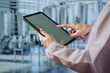 © Thitaporn - Asian young female quality control specialist holding a tablet in a modern dairy factory, approving production standards, ensuring food safety,hygiene compliance,smart manufacturing, industrial