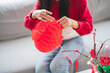 © Charlie's - Asian Woman decorated house for Chinese New Year Celebrations. putting traditional pendant to the Chinese Lunar New Year for good luck. Chinese word means blessing