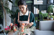 © Charlie's - Happy asian Woman arranging flowers caring for home greenery