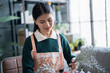 © Charlie's - Happy asian Woman arranging flowers caring for home greenery