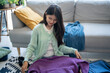 © Charlie's - Happy asian Woman packing suitcase for travel planning preparing vacation  in winter
