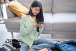 © Charlie's - Happy asian Woman doing checklist for packing suitcase before holidays trip.