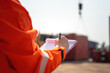 © Nattawit - An operation supervisor is writing on paper during perform safety audit at construction work site, with blurred background of heavy lifting operation. Industrial safe work practice concept scene.