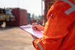 © Nattawit - An operation supervisor is writing on paper during perform safety audit at construction work site, with blurred background of heavy lifting operation. Industrial safe work practice concept scene.