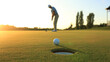 © Rajan - A golfer prepares to putt towards the hole on a lush green golf course