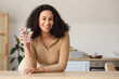 © Pixel-Shot - Young African-American woman with glass of water at table in kitchen