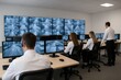 © whitestorm - Security control room with multiple monitors displaying live surveillance footage, employees monitoring the screens in a modern office environment.