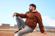 © Oscar - Young man relaxing on city wall looking away