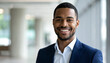 © Athiphat - Smiling young businessman with short brown hair beard blue suit white shirt confident professional modern office background natural light positive expression