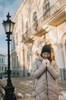 © Irina Magrelo - Woman stands outside a building during winter while holding her hands close to her chest