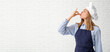 © Pixel-Shot - Young female chef in uniform making delicious gesture on white brick wall background