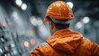 © liliyabatyrova - A dedicated worker in an orange jacket and helmet oversees machinery controls in a vibrant industrial facility, bustling with energy and activity under bright lights