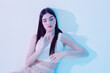 © SHOTPRIME STUDIO - Young woman with long dark hair poses in a white top against a light background. Soft lighting highlights her beauty and fashion style. Concept for beauty and fashion.