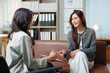 © MINAE - Two professional Asian businesswomen engaging in a focused discussion, one actively listening while the other explains a concept during a career coaching or mentoring meeting