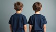 © miss irine - Two young boys stand with backs turned. They wear matching navy blue t-shirts and are positioned side by side against a plain gray studio backdrop. Their casual appearance suggests unity.