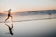 © qunica.com - A silhouette of a woman leaping along the shoreline at sunset, warm light and gentle waves create a dynamic, energetic mood ideal for fitness, travel, and lifestyle imagery.