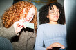 © Studio Marmellata - Two young women are looking at a laptop screen and holding a payment card, suggesting online shopping or a financial transaction.