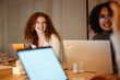 © Studio Marmellata - A diverse group of young professionals collaborate around a table with laptops, engaged in discussion and problem-solving.