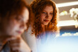 © Studio Marmellata - Two young women with curly red hair collaborate on a project, looking intently at a screen in a softly lit room.