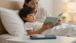 © sumon78 - Cozy parent and child reading bedtime book together during peaceful digital detox evening with smartphone set aside on nightstand promoting calm and family connection