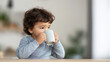 © Bonsales - Curious toddler gripping a cup with both hands, sipping a drink while practicing independent drinking skills