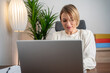 © Nenad - Middle age European business woman CEO using laptop application for work at table workspace in office. Smiling Latin Hispanic mature adult professional businesswoman using pc digital computer.