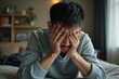 © Yuliia - Asian Man at Home Experiencing Emotional Distress and Struggling with Mental Health