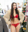 © JackF - Young woman selects and tries on lace lingerie and fur coat in fashion boutique decorated for New Year
