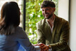 © Alaphotography - Man and woman shake hands in a bright room with green outdoor view during a meeting or conversation in the late afternoon