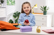 © New Africa - Girl with apple packing her backpack for school at desk indoors