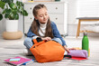 © New Africa - Girl packing her backpack for school at home