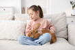 © New Africa - Girl with cute bunny on sofa at home