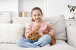 © New Africa - Girl with cute bunny on sofa at home