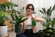 © New Africa - Woman spraying beautiful potted houseplant with water indoors