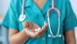 © LittleDreamStocks - Healthcare professional in medical scrubs holding white tablets in palm, symbolizing prescription medication, treatment plan, and patient care concept.