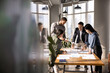 © fizkes - Four diverse business analysts discussing paper reports at meeting table, analyzing statistic research results, working together in business plan for project growth. Candid shot with copy space