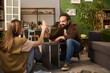 © pressmaster - Caucasian young adult man and Caucasian young adult woman assembling furniture together in living room, smiling and giving high five while sitting on floor, teamwork and collaboration