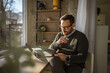 © Miljan Živković - Smiling man working remotely using laptop at home office