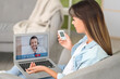 © Pixel-Shot - Diabetic young woman with glucometer receiving online consultation from doctor in armchair at home