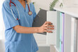 © Pixel-Shot - Mature female doctor taking folder from shelf in clinic, closeup
