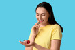 © Pixel-Shot - Beautiful young woman with chocolate covered strawberry and fresh berry on blue background