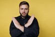 © bodnarphoto - Confident man expressing refusal with crossed arms against a bright yellow background